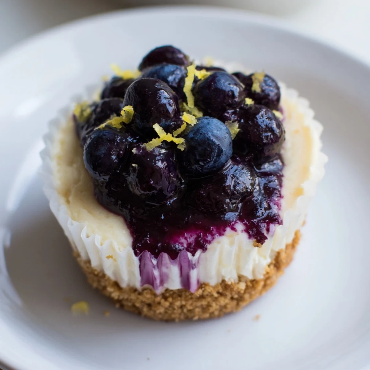 Golden mini lemon blueberry cheesecakes topped with vibrant berry compote on graham crusts