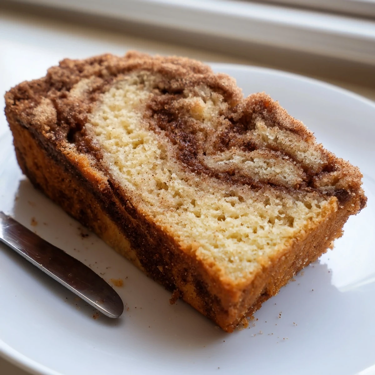 Moist snickerdoodle banana bread loaf topped with crackly cinnamon sugar, sliced on a wire rack