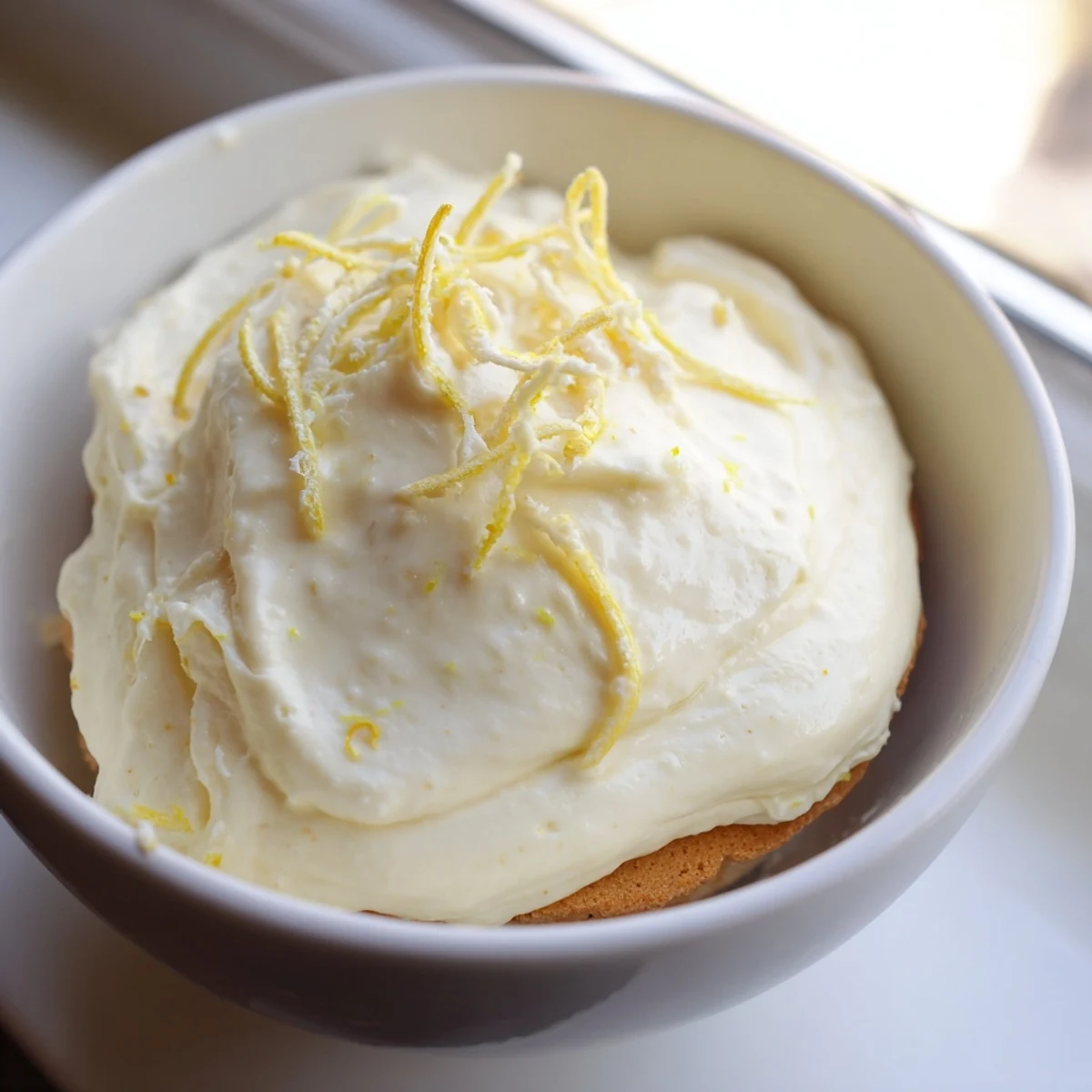 Layers of creamy lemon tiramisu topped with fresh zest in a glass dish