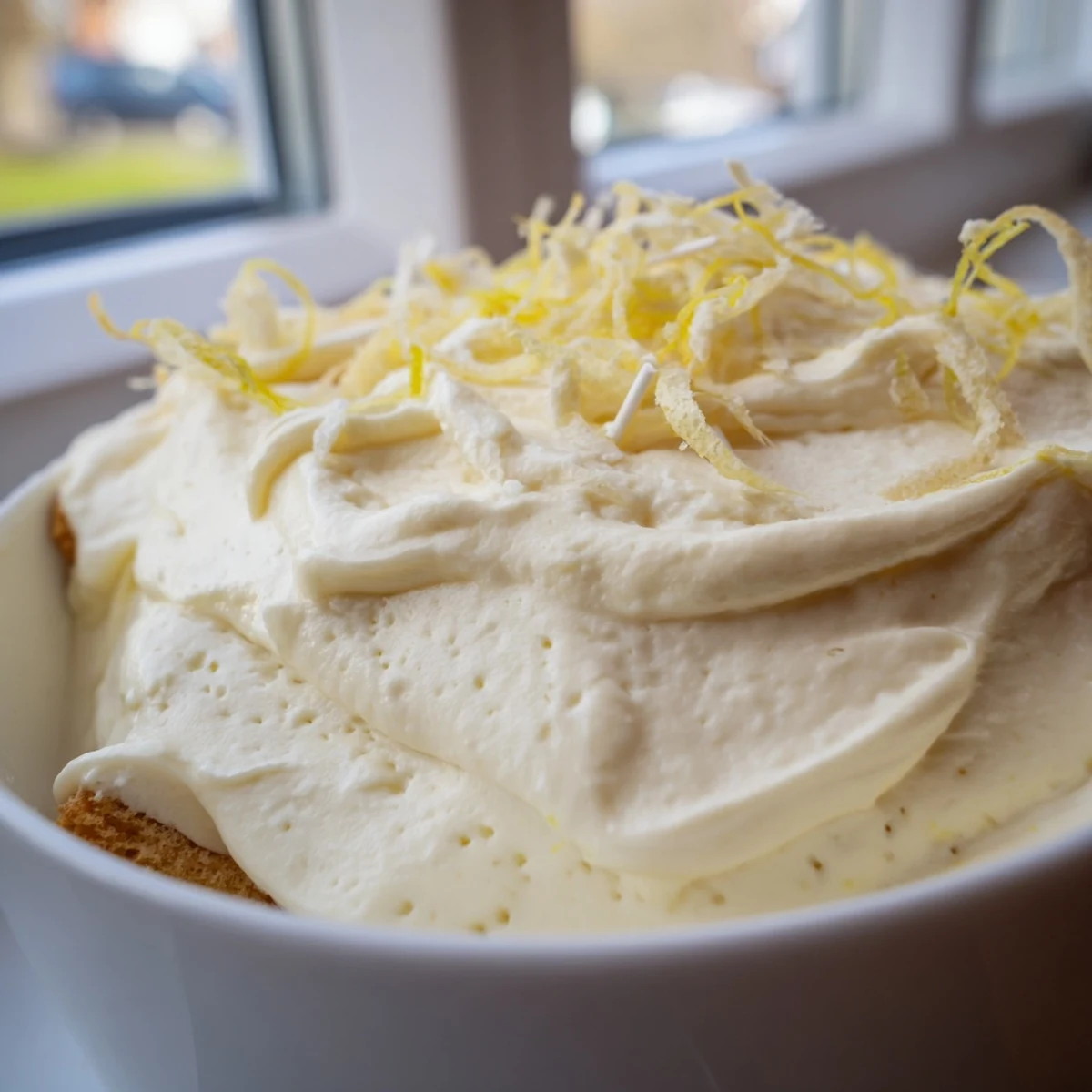 Chilled lemon tiramisu garnished with white chocolate curls on a summer dessert plate