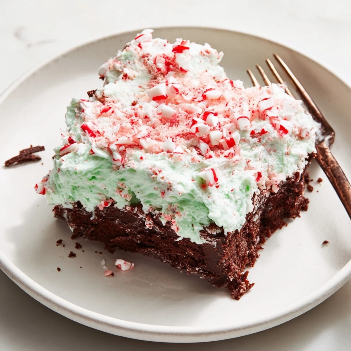 Peppermint Poke Cake drizzled with whipped topping, crushed candies, chilled and ready