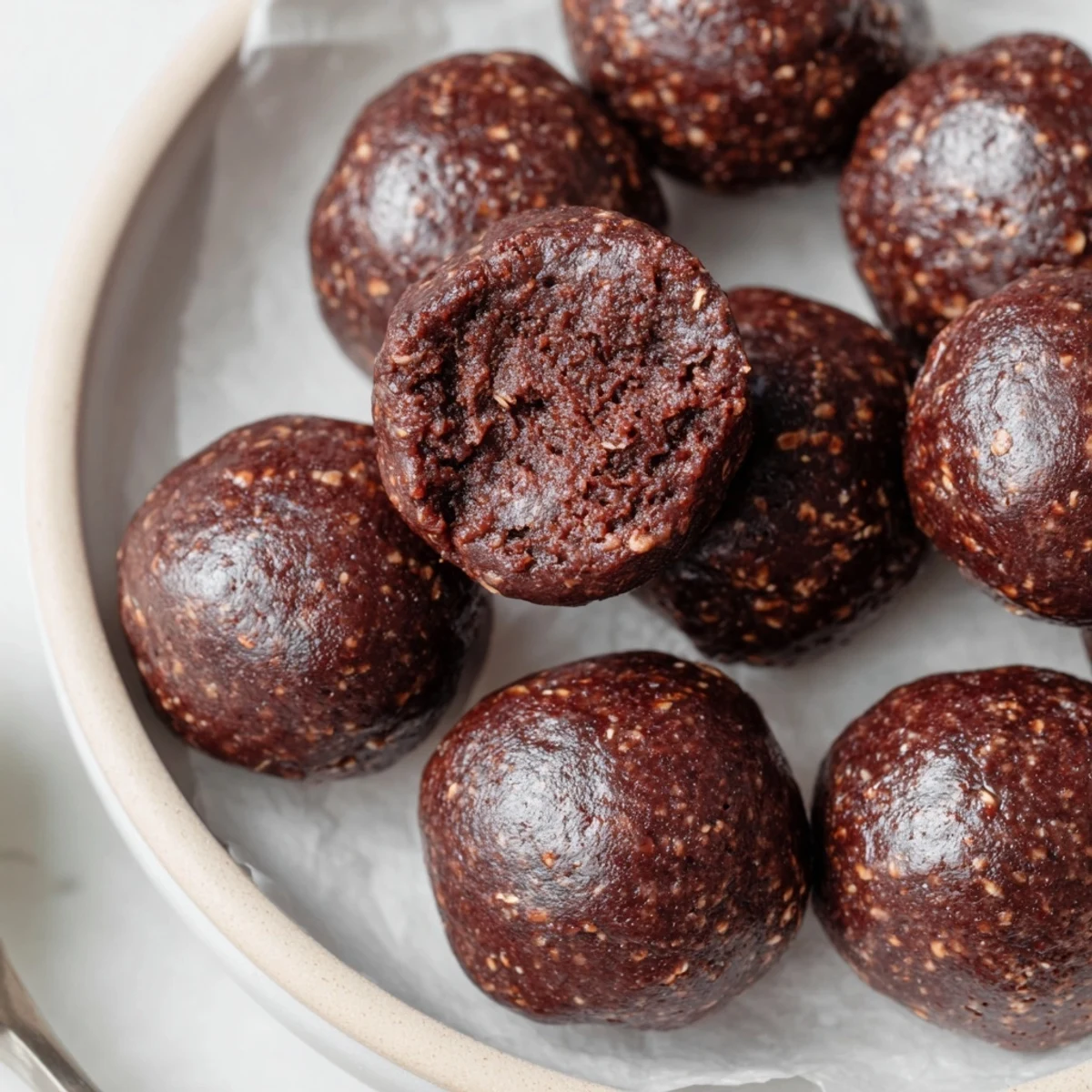 Tray of Brownie Protein Bites on parchment, fudgy chocolate sheen  