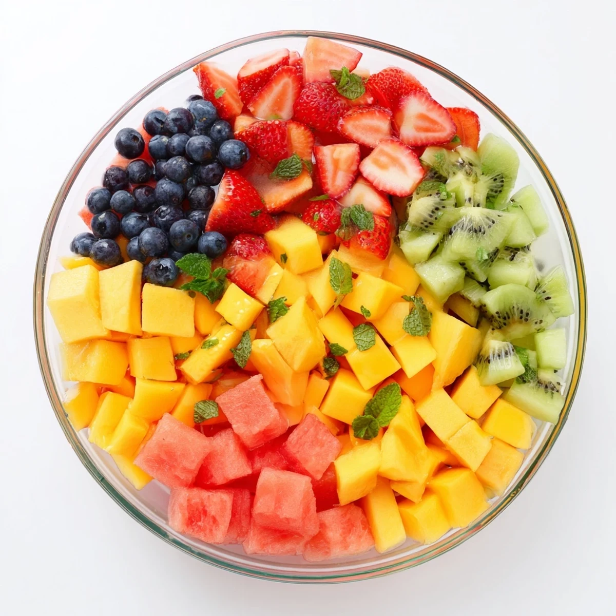 Vibrant mixed fruit summer delights topped with fresh mint and citrus honey syrup