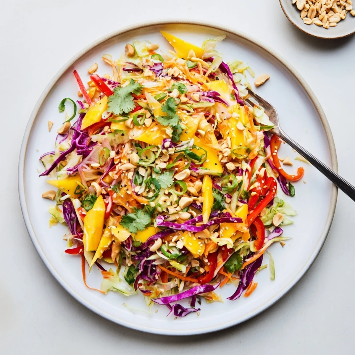 Golden refreshing mango slaw recipe with crunchy shredded vegetables and fresh cilantro garnished with sesame seeds.