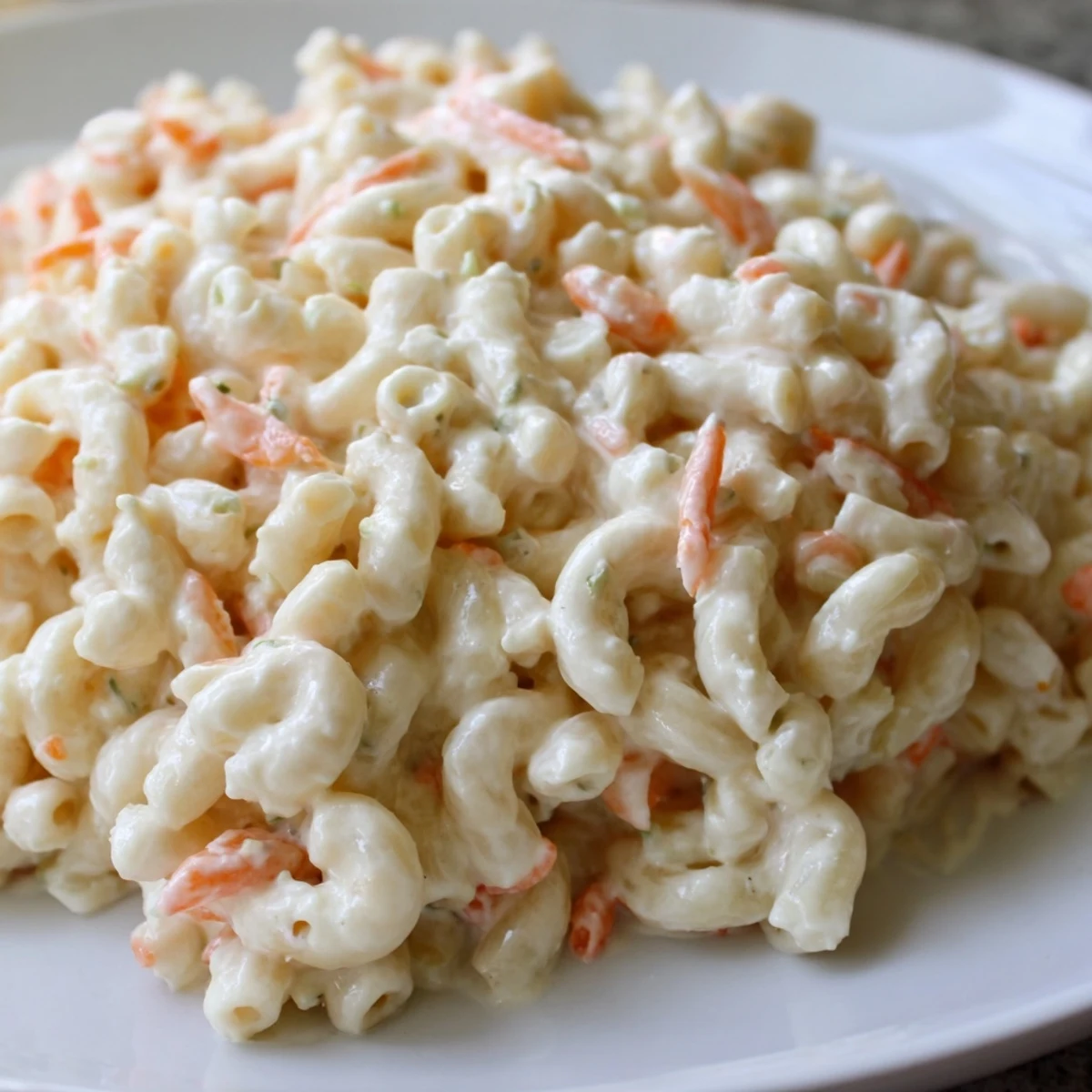 Vibrant Hawaiian style mac salad bowl showcasing colorful vegetable flecks throughout the rich velvety coated elbow macaroni