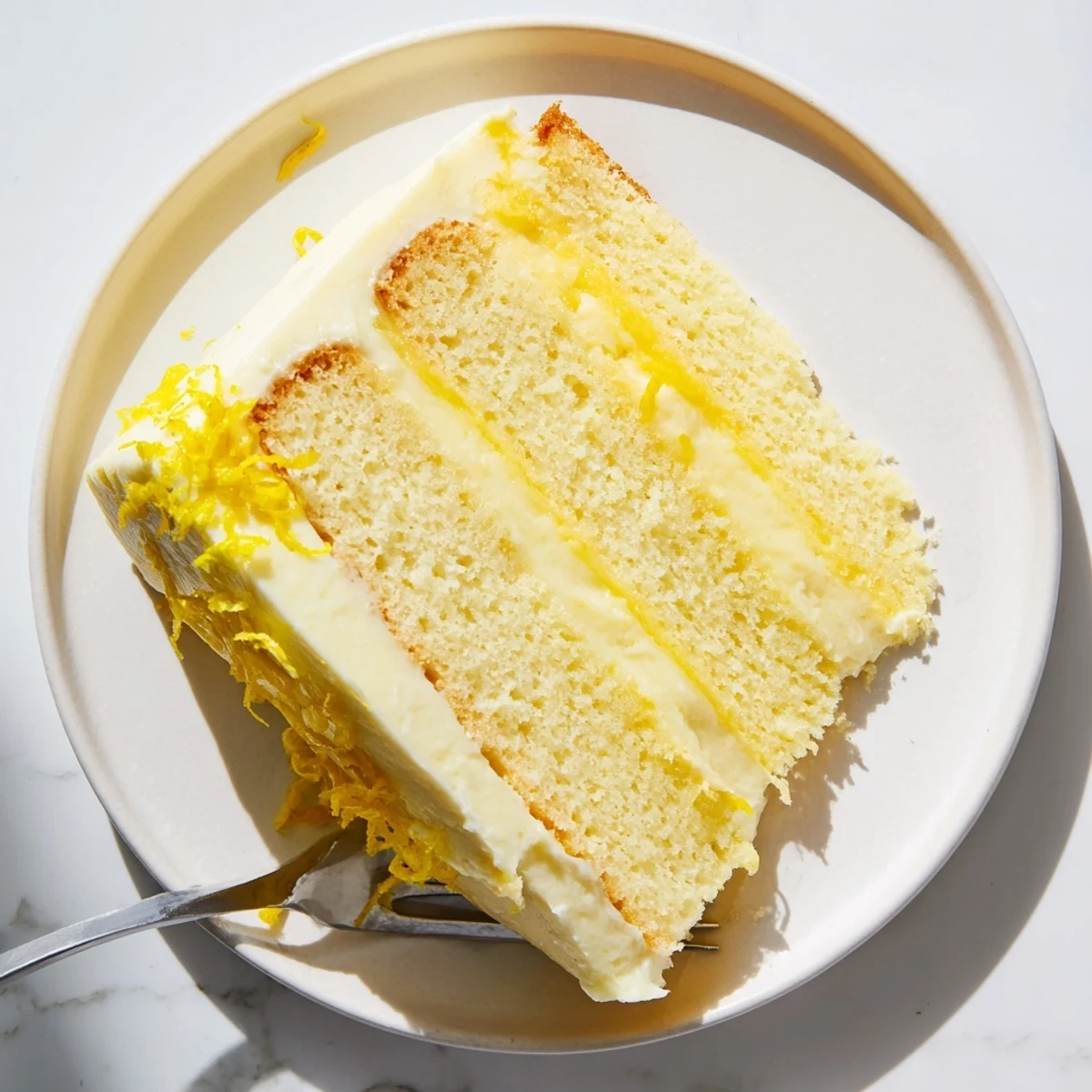 Three-tier lemon layer cake sliced to reveal zesty curd between fluffy yellow sponge layers