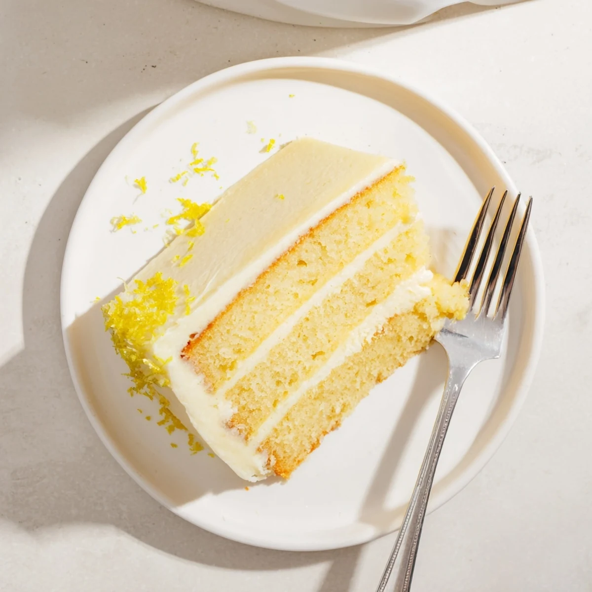 Elegant lemon layer cake topped with smooth buttercream and garnished with fresh lemon zest