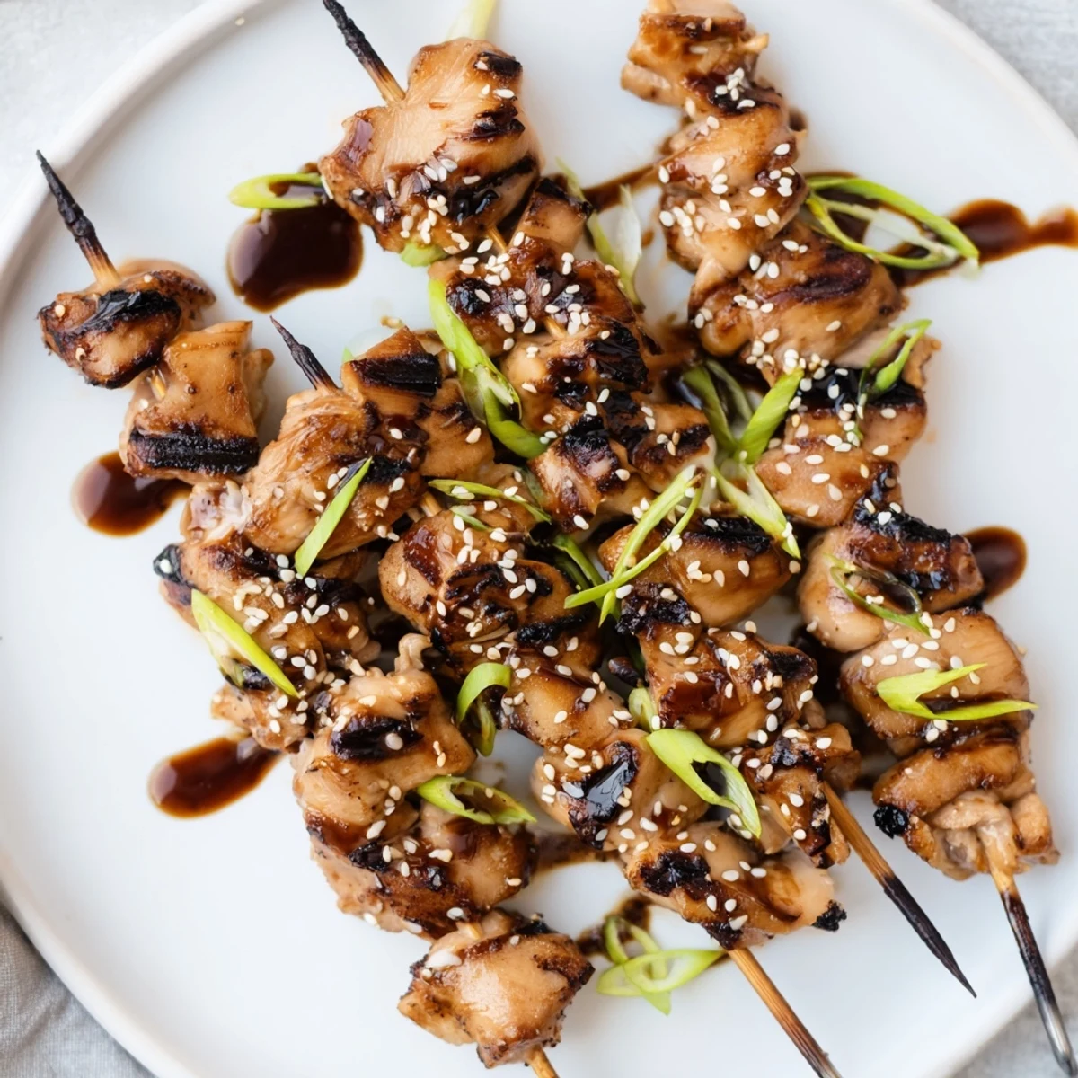Grilled Bang Bang Chicken Skewers drizzled with sesame garnish, served on platter