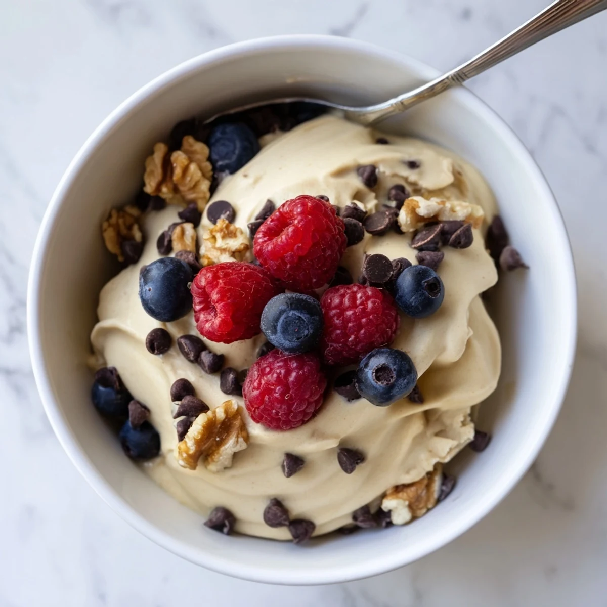 Vegan banana nice cream swirling with chocolate sauce served in a glass dessert bowl