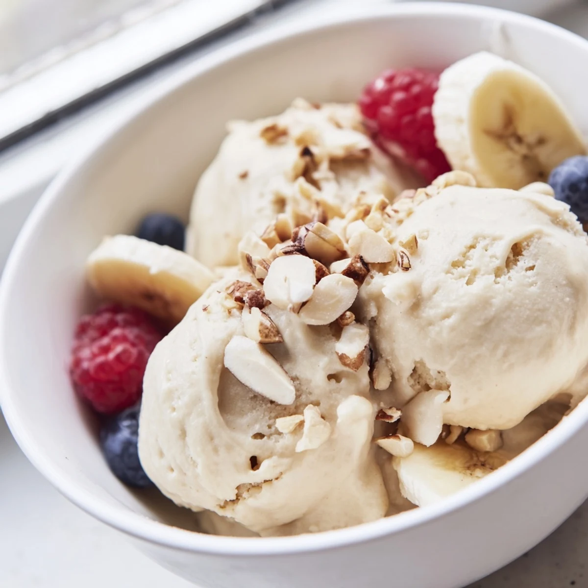Creamy healthy nice cream scooped into bowls topped with fresh fruit and chopped nuts