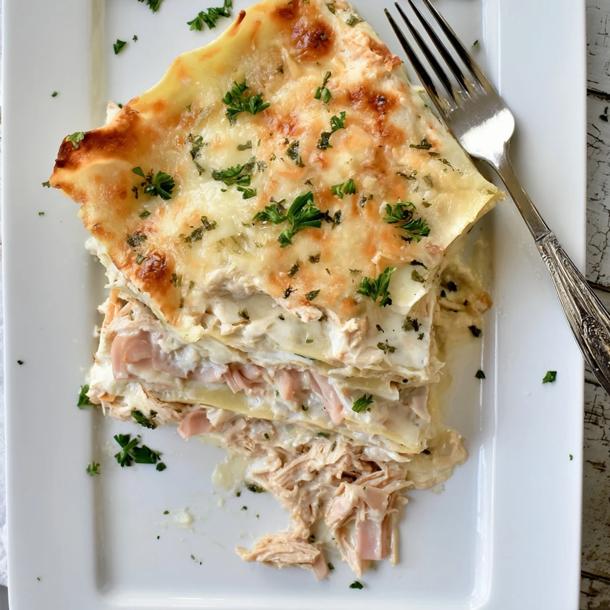 Chicken Cordon Bleu Lasagna casserole sprinkled with fresh parsley on white serving platter