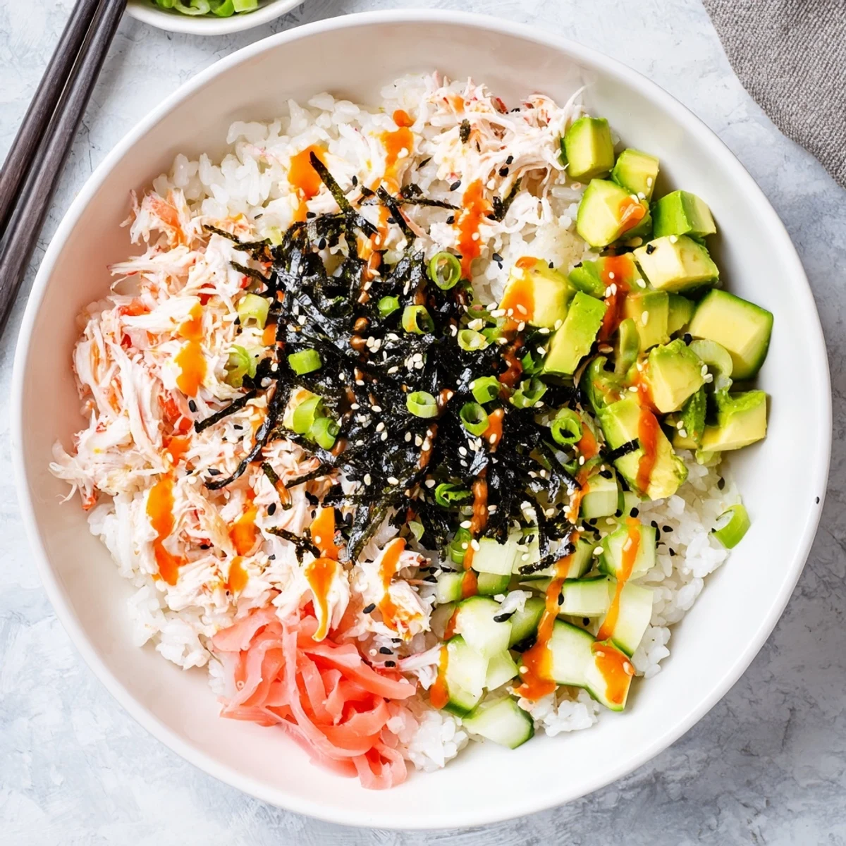 Colorful California roll sushi bowls topped with crab, avocado, cucumber and sesame seeds