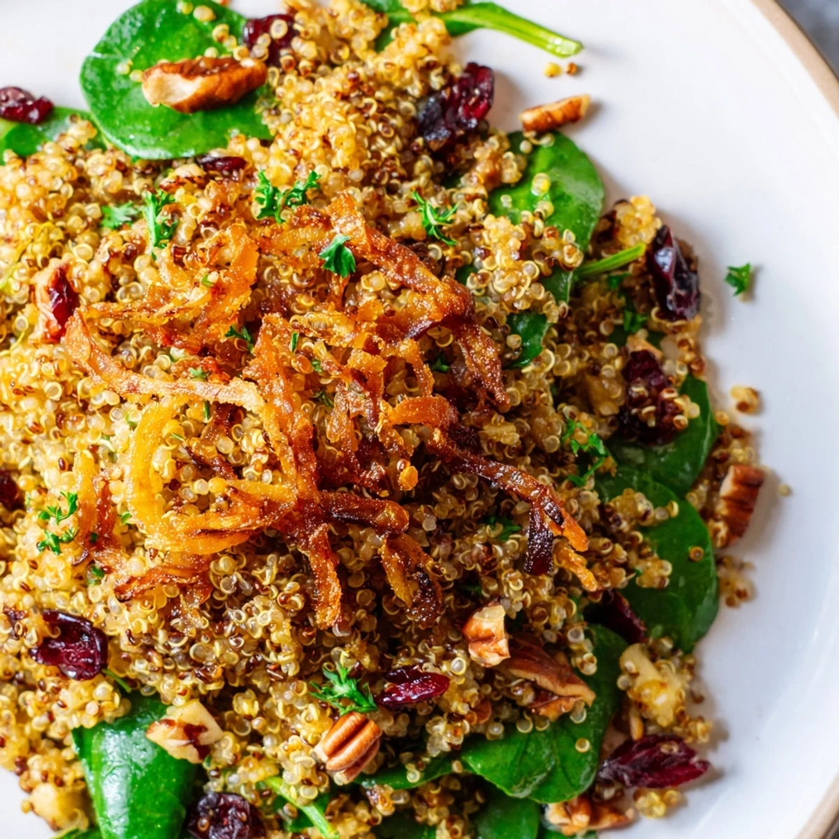 Golden crispy shallots crown a colorful honey mustard quinoa apple salad in a wooden bowl