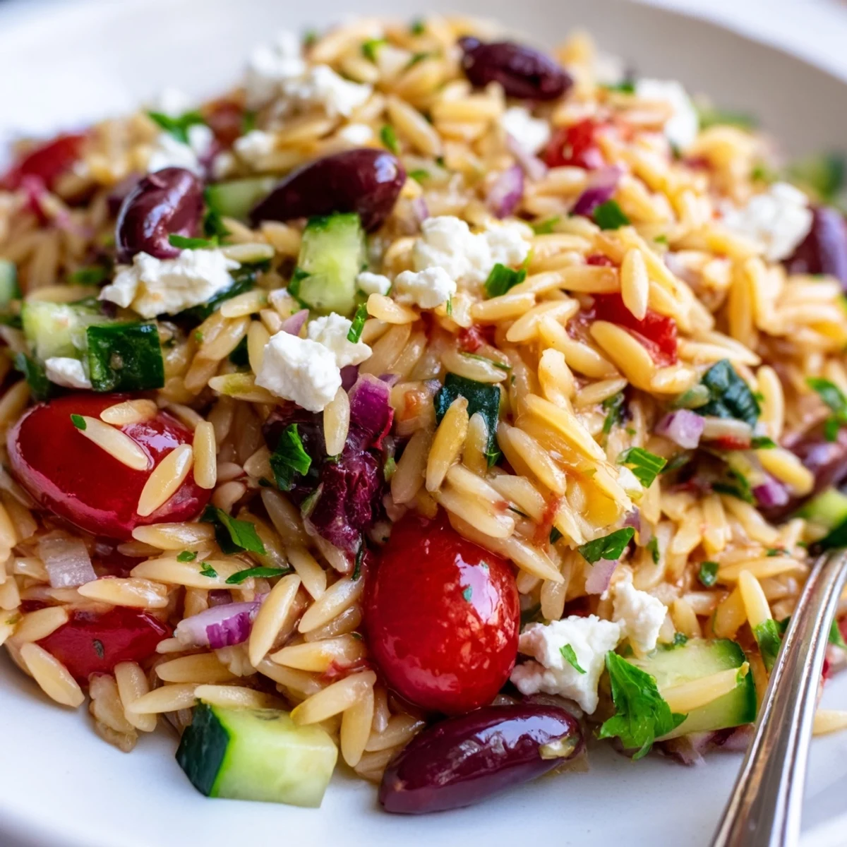 Cool Mediterranean orzo pasta salad in a bowl, topped with crumbled feta and parsley