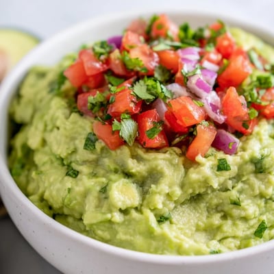 Creamy homemade guacamole with zesty tomato pico de gallo, ready to serve as a colorful party appetizer.
