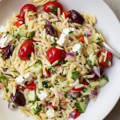 Vibrant Mediterranean orzo pasta salad glistening with herb dressing and fresh crisp veggies
