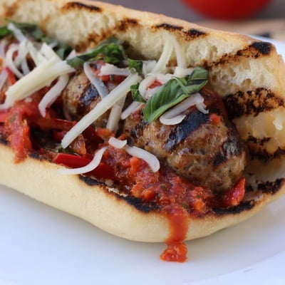 Juicy grilled sausage grinders topped with melted cheese and smoky tomato sauce