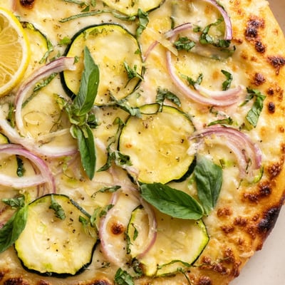 Vegetarian pizza topped with creamy lemon ricotta, zucchini ribbons, and red onion.